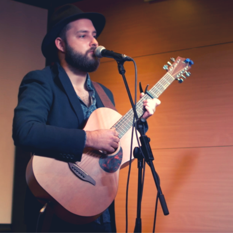 Wykonawca w kapeluszu i z gitara podczas wystepu
