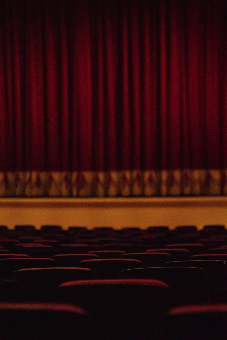 Puste fotele teatralne i scena zasłonięta kurtyną
